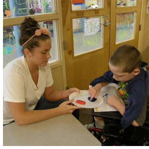 Summer Siblings group leader Maura Loftus helps Ryan Maude of Palatine with painting while he waits for his siblings to join him after therapy. 