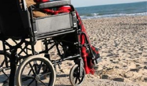 a wheelchair stopped at a curb looking out at a beach
