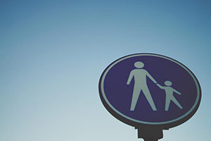 A blue, circle sign with a parent holding the hand of a child.