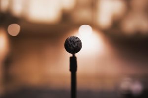 A microphone in focus with an auditorium in the background, out of focus