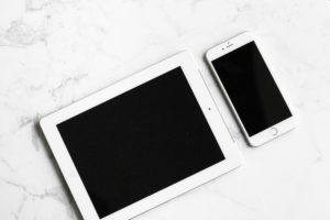 An iPad next to an iPhone against a marble background