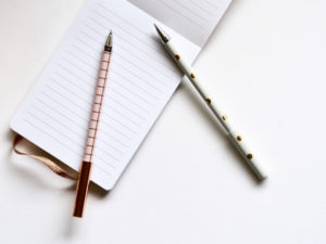 Two pens laid over a lined notebook