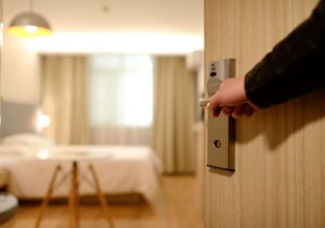 A hand opening a door to a hotel room