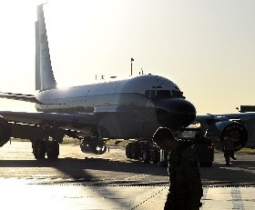 a wide view of an airplane  stationary at an airport, sun low in the background