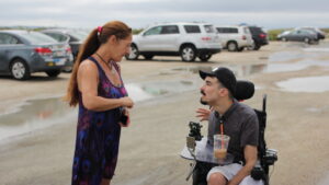 Alexander in his wheelchair filming with a woman in a parking lot