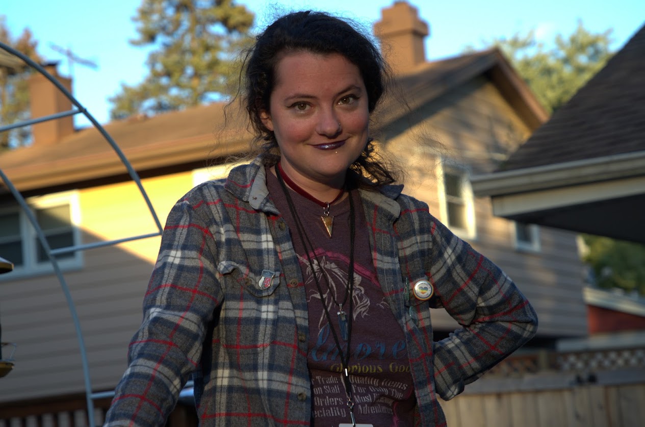 Anna outdoors, wearing a plaid shirt and smiling