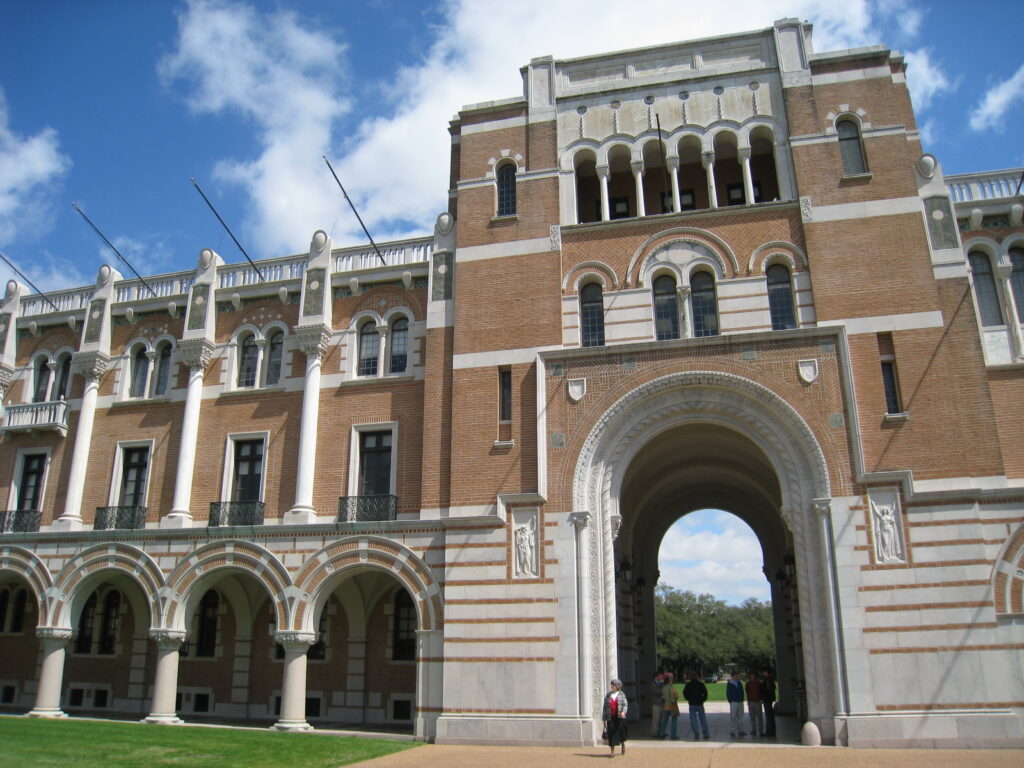 A tall building, historical looking, on a college campus. The building has a big archway. 