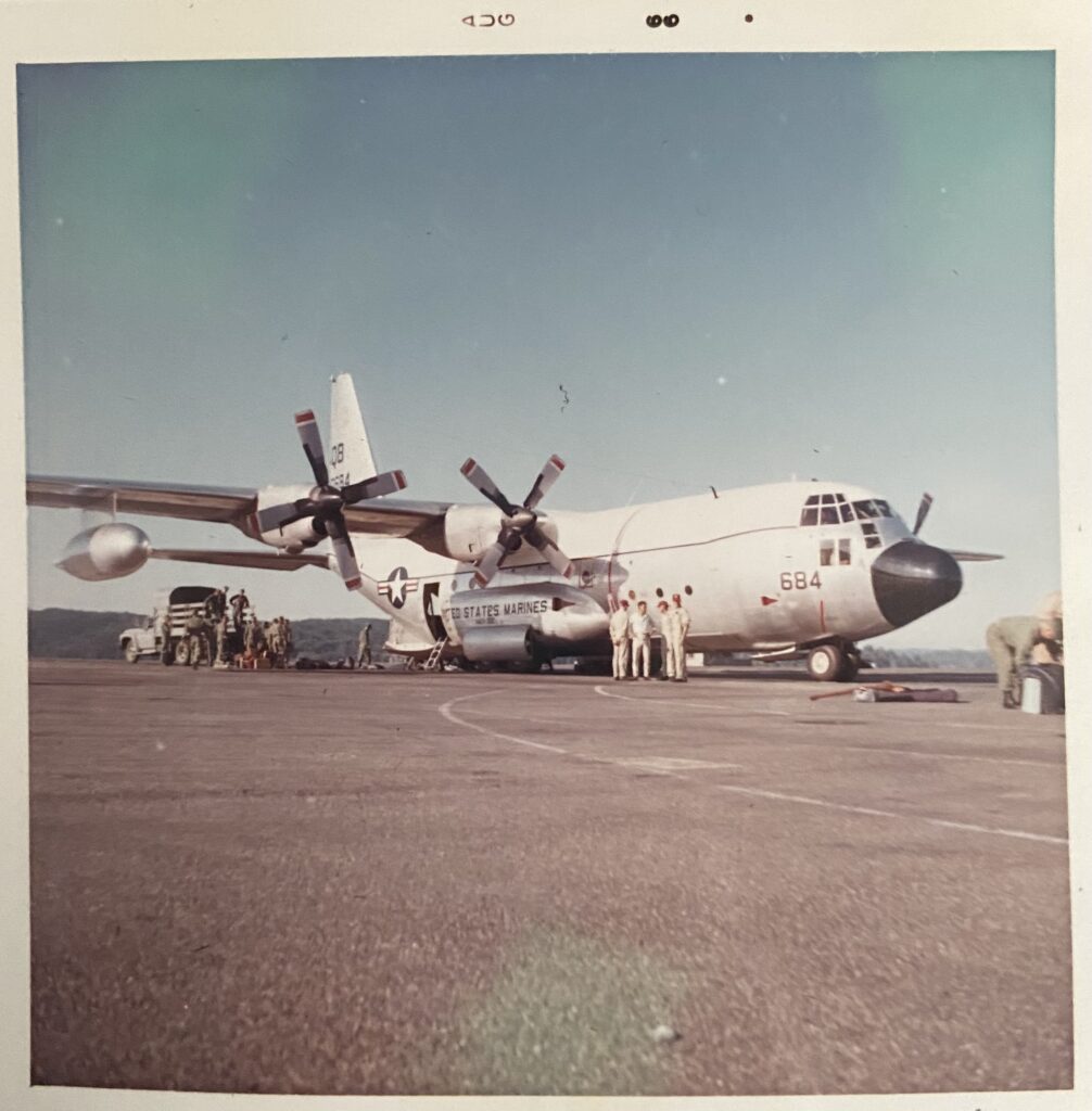 An old plane with Marines standing around it. The photo is in color, but from the 60s 