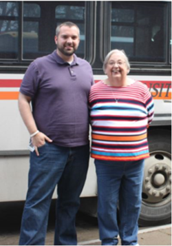 Jeremy standing next to his aunt, and both standing beside a bus.