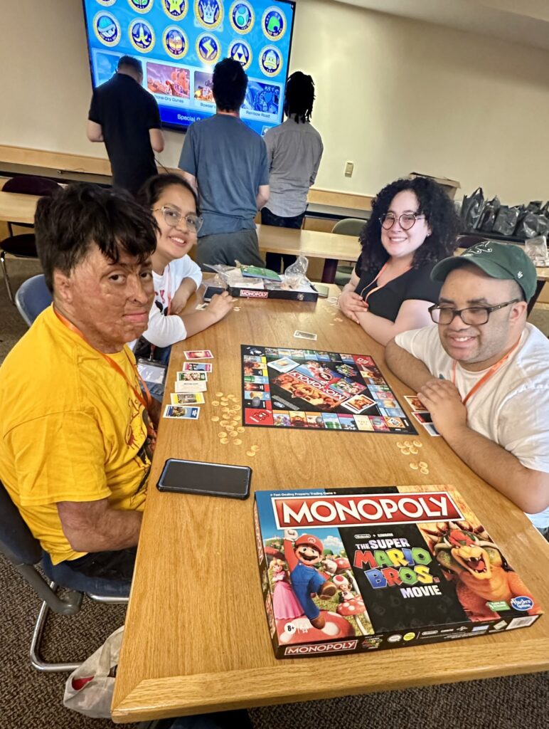 Four people with disabilities playing Super Mario Monopoly at the Retreat