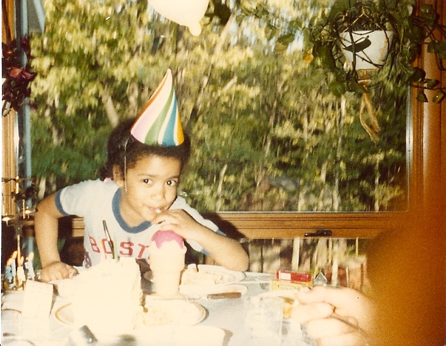 Jen as a child wearing a birthday hat