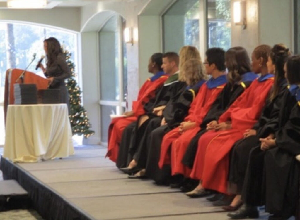 Andrea speaking at a podium to a graduating class