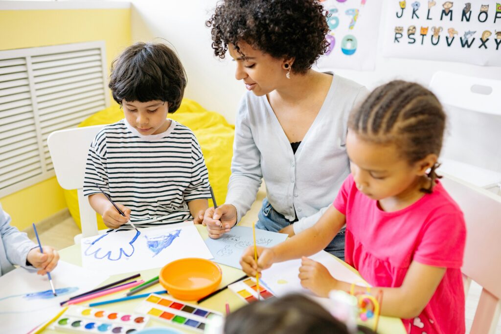 A woman in a classroom teaching two young children