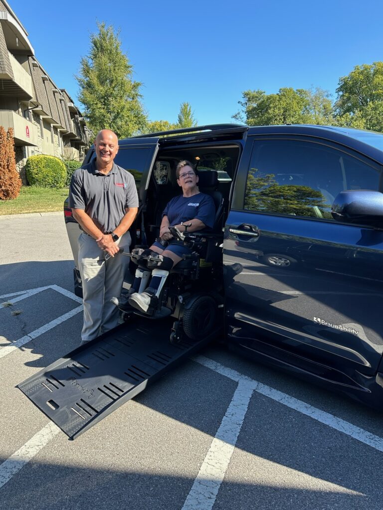 Rhonda, using her wheelchair, on a ramp inside an accessible van. She is next to Mike Smith with Superior Van & Mobility of Louisville, KY