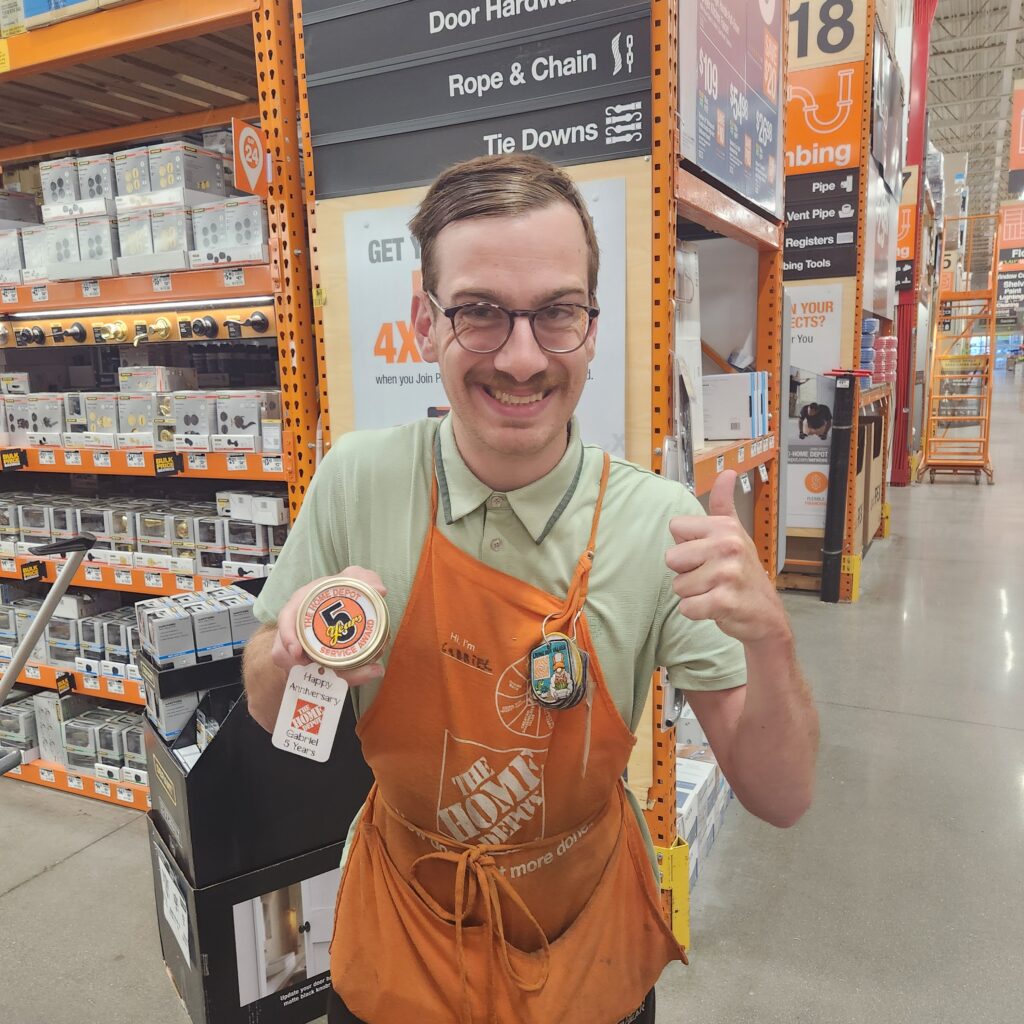 A Home Depot employee holding up his 5-year service badge