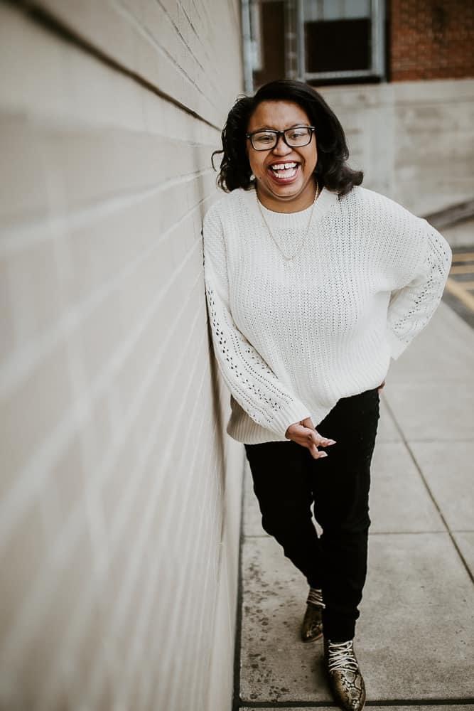 Keah smiling, leaning against a wall